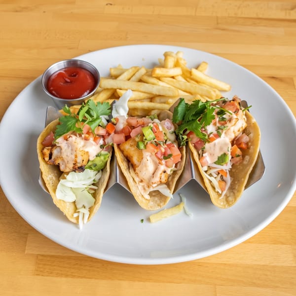 Three fish tacos with pico de gallo, sauce, and cilantro, served with fries and ketchup.